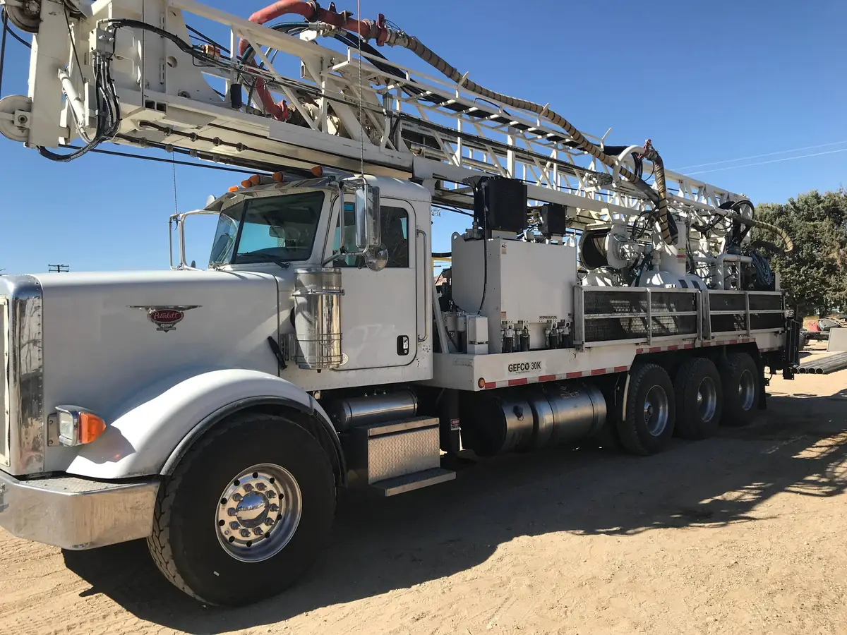 Superior’s white Peterbilt well drilling rig parked on a desert lot with Joshua trees